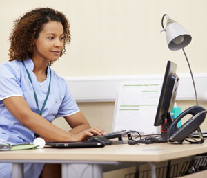 health care worker entering information at a computer