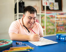 Young man with special needs painting in the classroom at school.