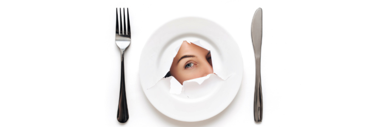 dinner plate with paper-like rip in the middle featuring woman's eye looking through. there is a fork on the left side of the plate and a knife on the right side of the plate.