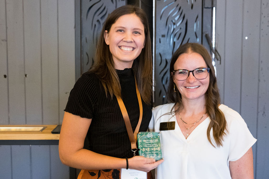 Two women holding the CSU Best P2 Project Award Winner trophy