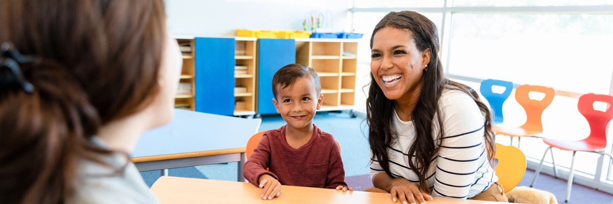 Latinx mom and child meet with teacher in classroom