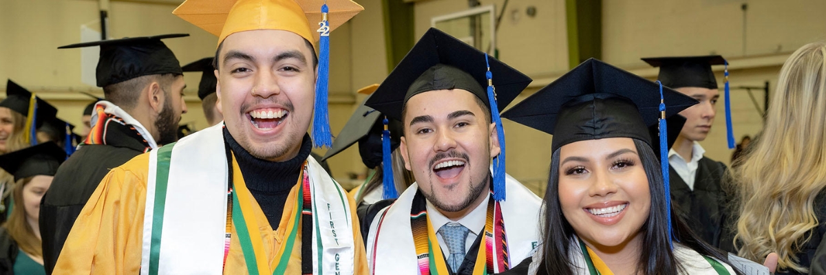 three Hispanic students at a graduation ceremony
