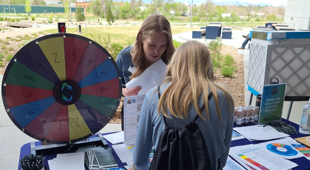 Air division staff at a tabling event with a large colorful spinning game.