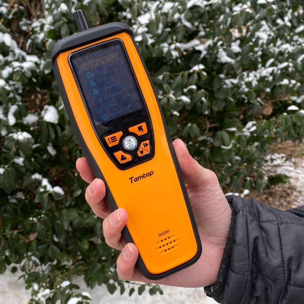 Person's hand holding an air sensor.