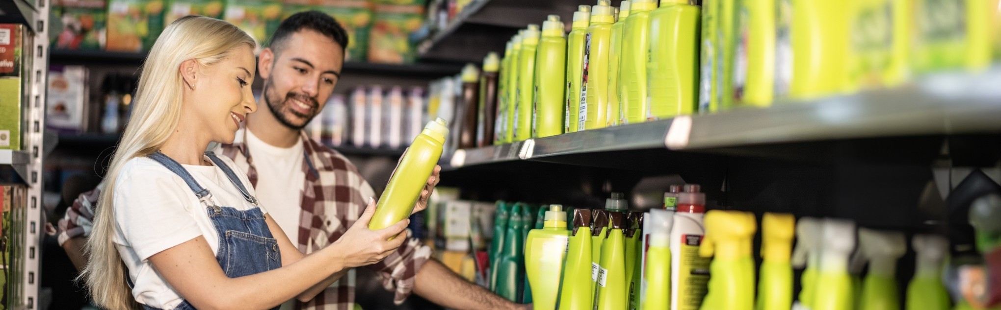 A couple in a store exam the label on the back of a spray bottle.