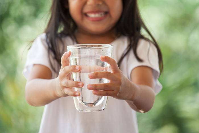 young child holding a glass of water