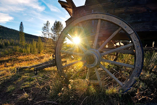 Wagon wheel in a wooden cart with sun light shining through. 