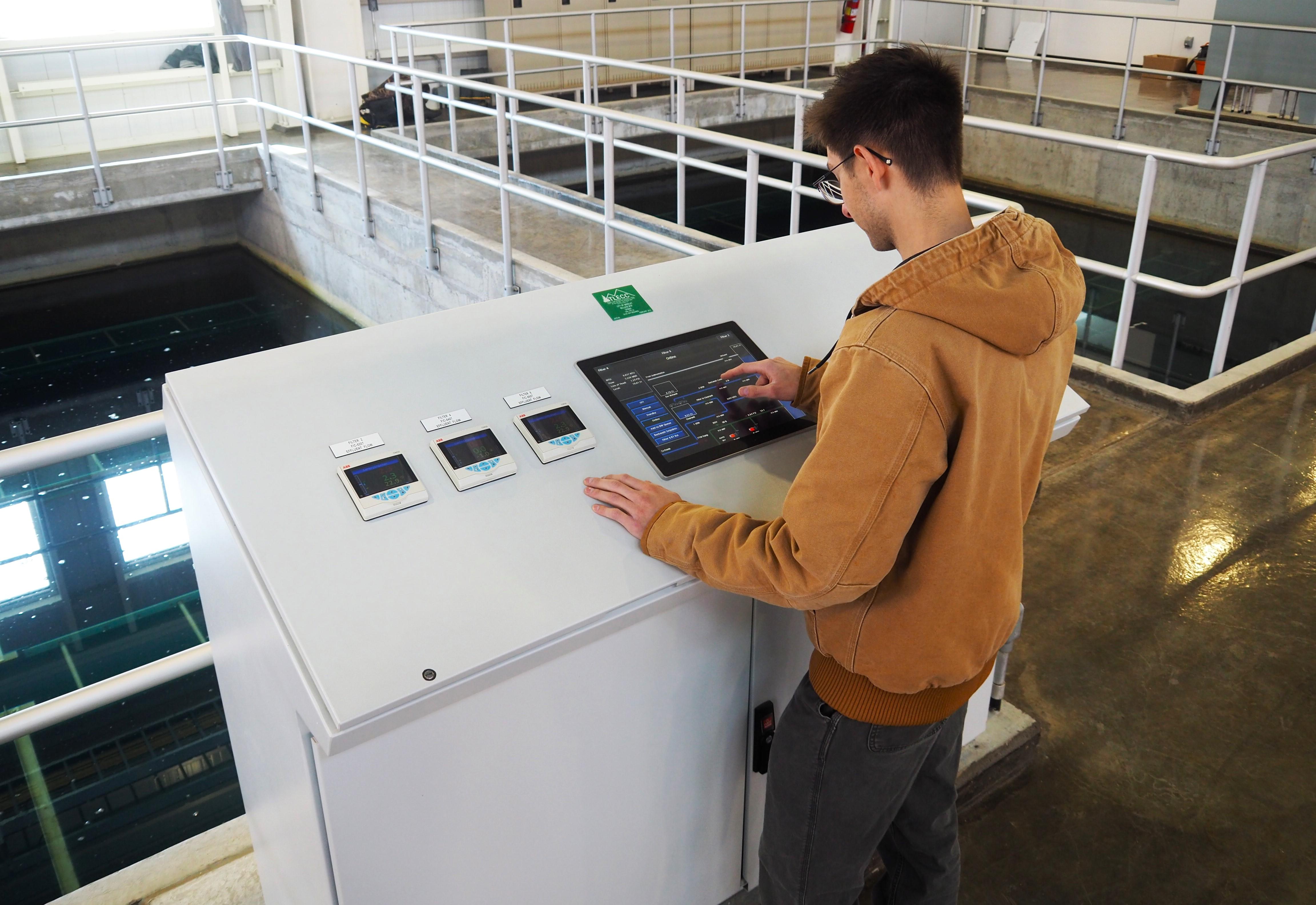 male clean water technician standing over equipment working