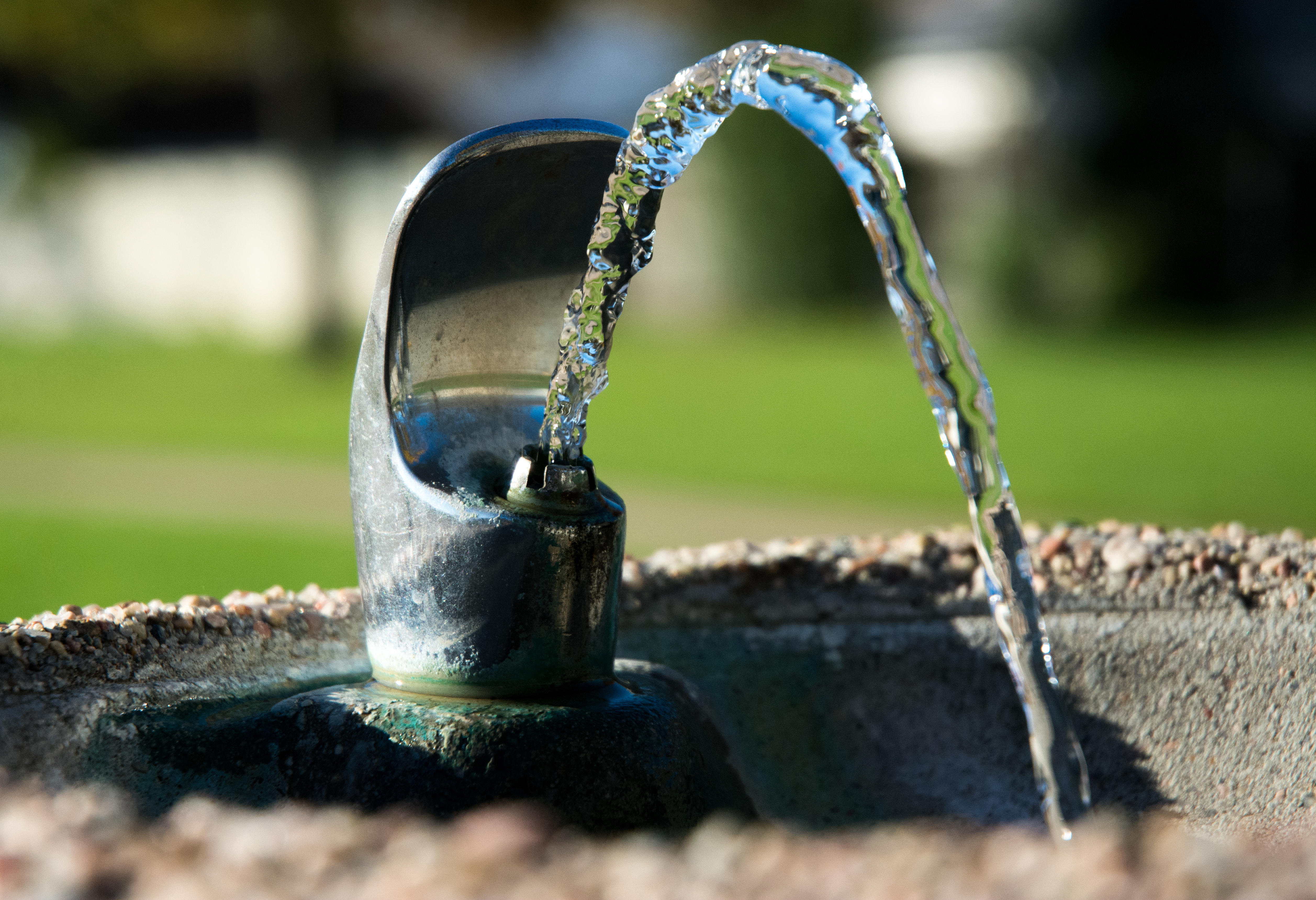 Outdoor water fountain spout with water flowing out. 