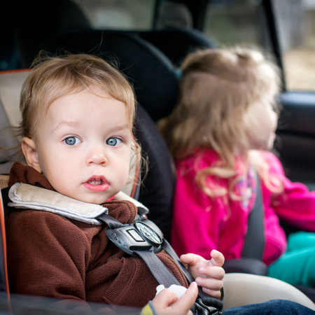 Two young children in car with seatbelts fastened