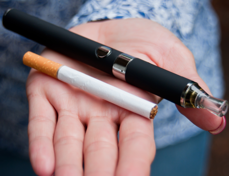 Cigarette and vaping pen in hand