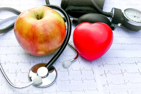 stylized heart, apple, and stethoscope arranged on some eeg readout papers