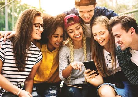 smiling teens gathered around a phone