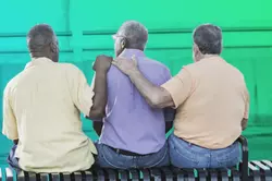 Three men sitting on a bench facing away from the camera. They are patting each other's backs.
