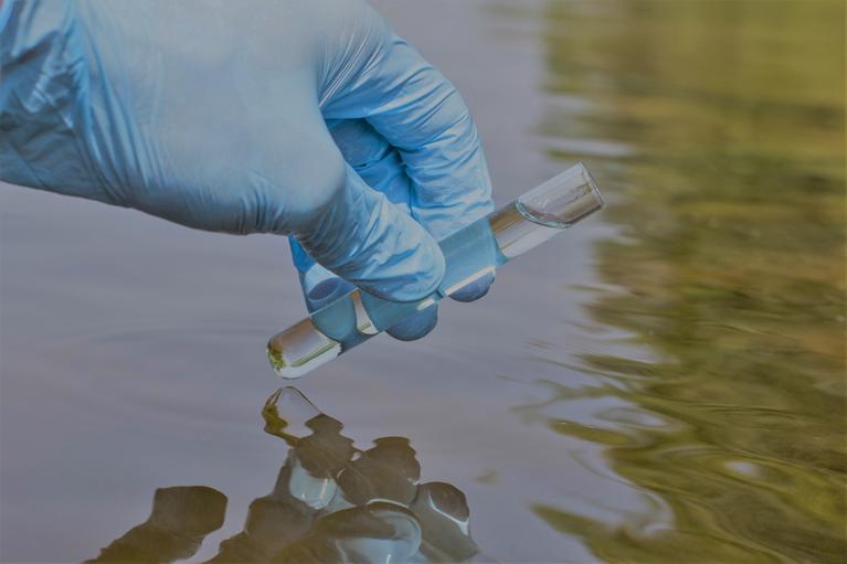 Gloved hand collecting a water sample