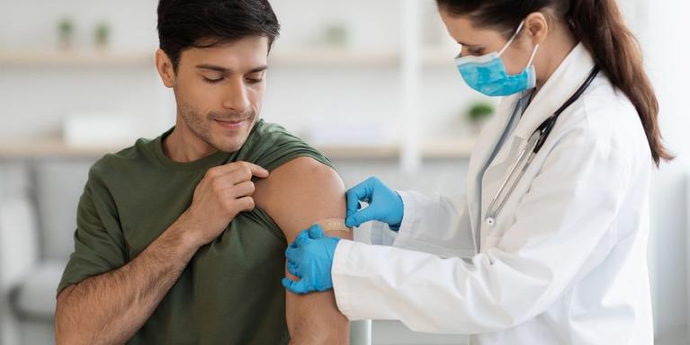 Healthcare provider puts bandaid on Latinx man's arm after vaccination