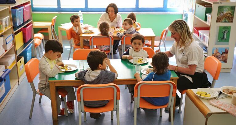 Young children eating and drinking with caregiver