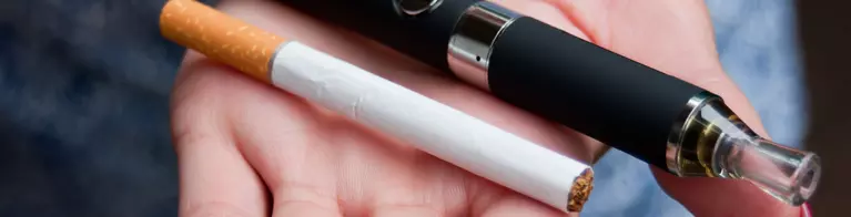 Cigarette and vape pen in hand