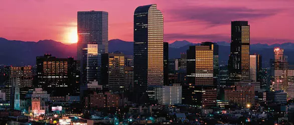 Denver skyline against a sunset over mountains