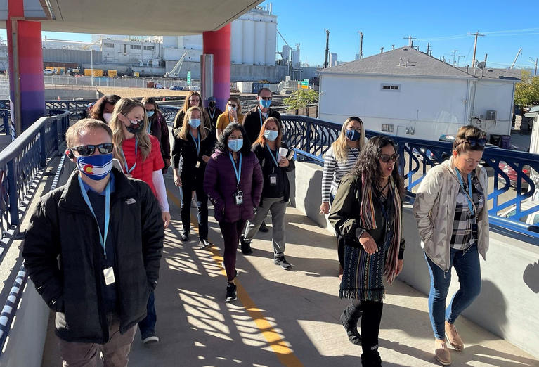 Group of CDPHE staff and Elyria-Swanson community members walking on bridge during a tour