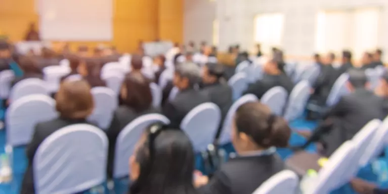 Stock image of people sitting in a community meeting or conference presentation