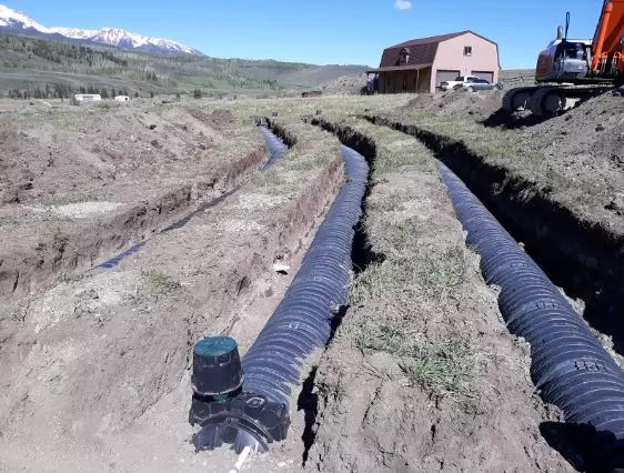 two side by side black pipelines embedded in dry earth