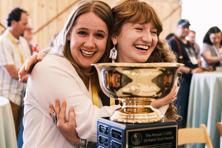 Two of the Alliance Center’s representatives hug and pose with their 24-Karat Gold Award trophy after winning the 2023 award.