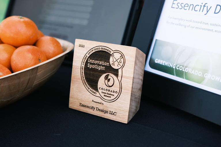Up close of Essencify Design’s 2023 Innovation Spotlight Award, a wooden award with the Innovation Spotlight Award logo, the year 2023, and their name.