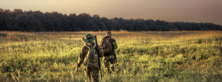 Hunters walking through open grassland