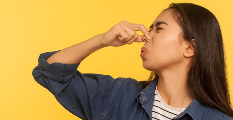 Girl pinching her nose from a bad odor.