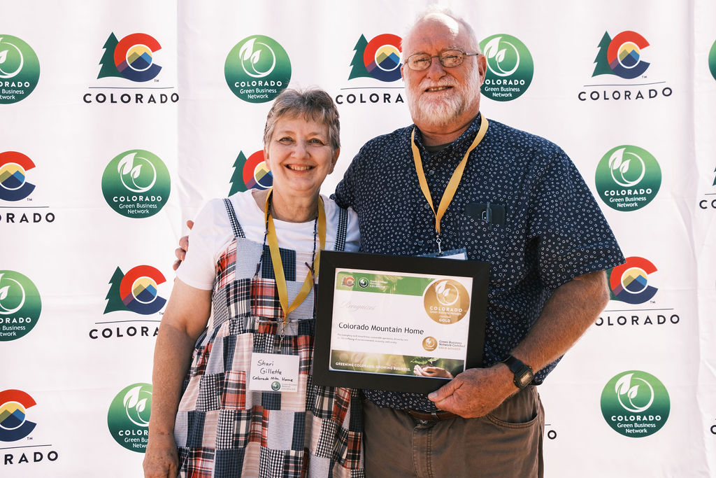 Two representatives from Colorado Mountain Home stand in front of the CGBN banner, holding their framed Gold-certified certificate.